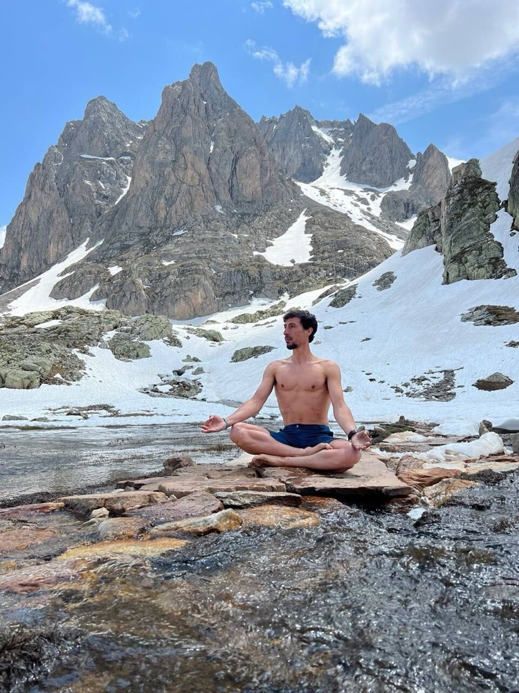 Leonardo Pelagotti en méditation au pied d'un sommet enneigé